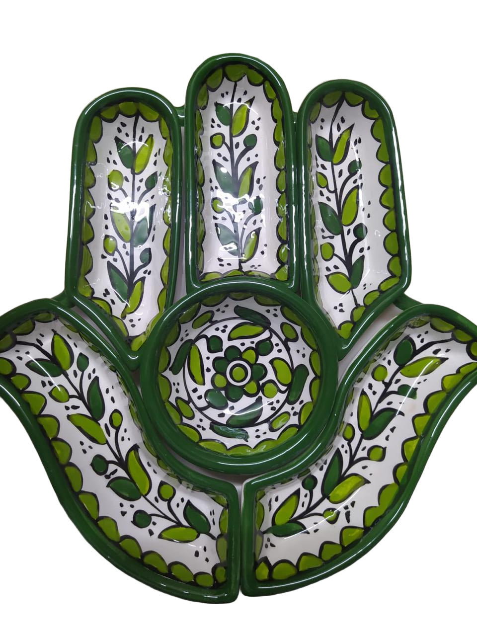 Decorative ceramic dish with green and white floral patterns on a white surface.