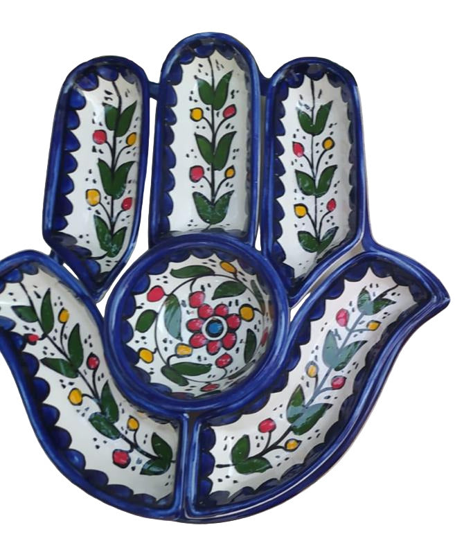Decorative ceramic hand-shaped plates with floral patterns on a tiled floor.